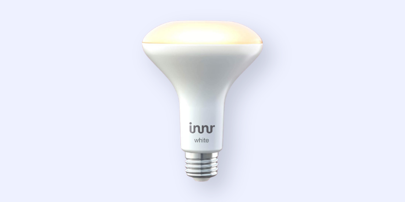 A white LED light bulb with a wide, rounded top, slightly glowing yellow, labeled innr white on the lower part, against a light gray background.