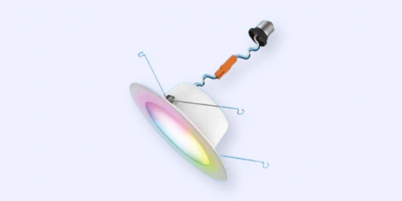A recessed LED downlight with a white trim, multicolored lighting, two blue spring clips for mounting, and a connected socket adapter with an orange wire connector.