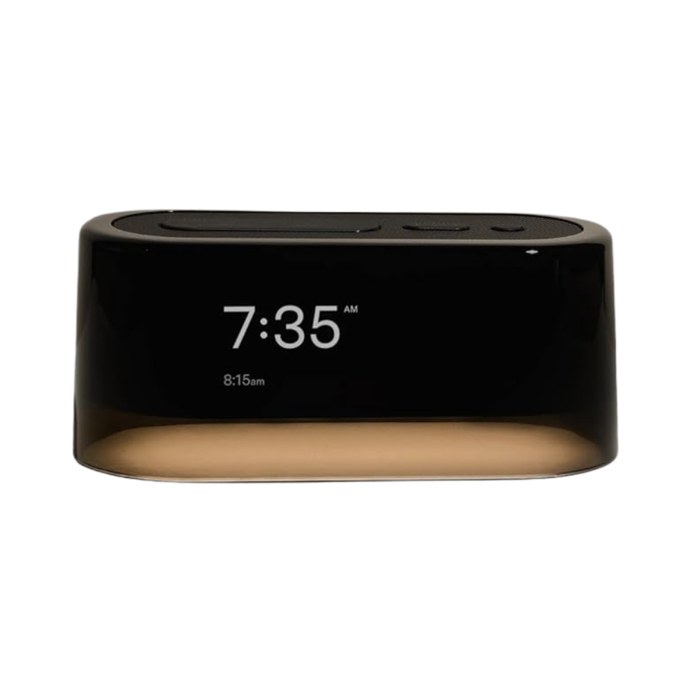 Black digital alarm clock displaying 7:35 AM with ambient nightlight glow and wireless charging pad on top