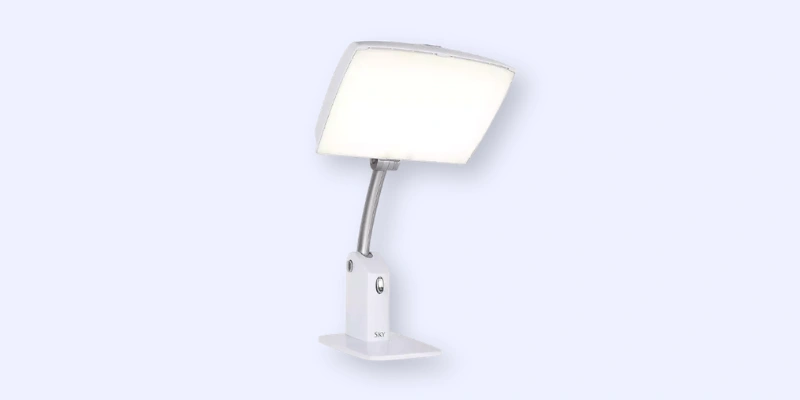 A white, modern desktop lamp with a rectangular light panel and an adjustable neck, mounted on a small base against a light blue background.