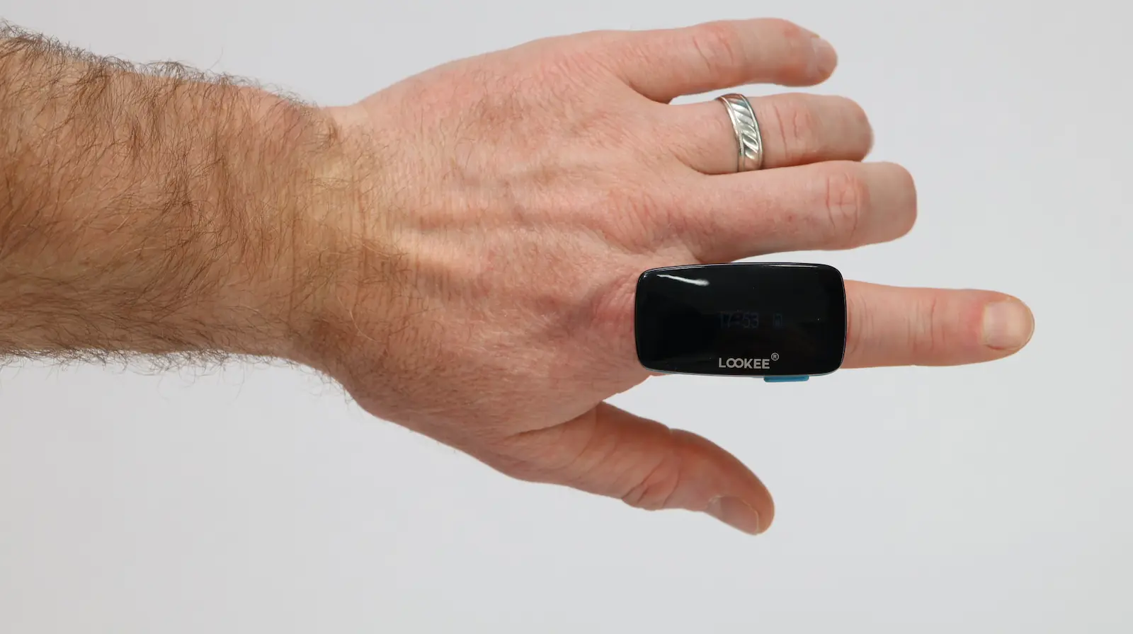A hand with a silver ring on the ring finger is shown wearing a black electronic device labeled LOCKEE on the index finger against a plain white background.