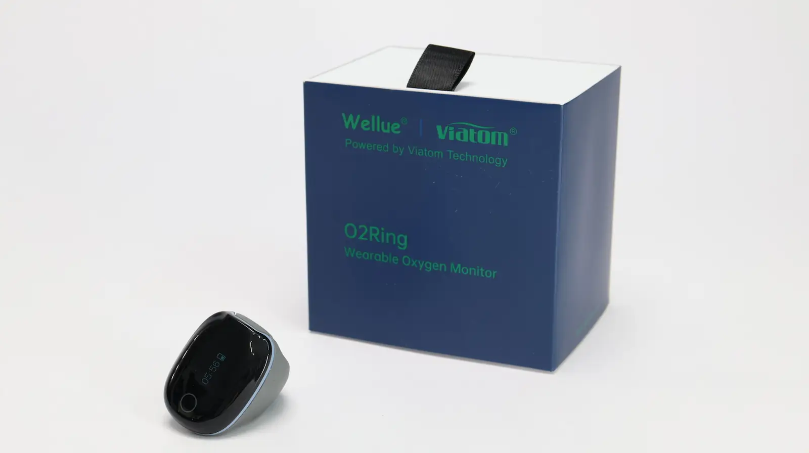A blue box labeled Wellue Viatom O2Ring Wearable Oxygen Monitor stands next to a black, oval-shaped electronic device with a display screen, both on a white background.