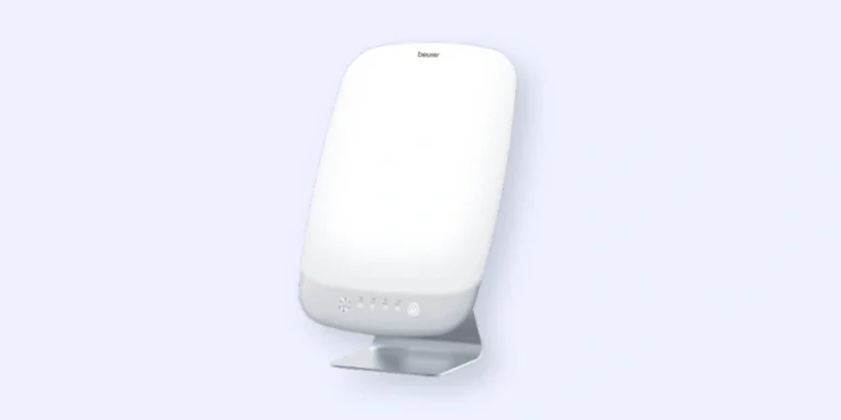 A white, rectangular light therapy lamp with a simple design, standing on a small silver stand against a light background. The lamp has control buttons on the lower front.