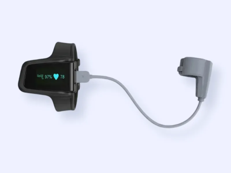 A wearable medical device with a display showing SpO2 97% and heart rate 78, connected by a cable to a gray finger or wrist sensor, on a light background.