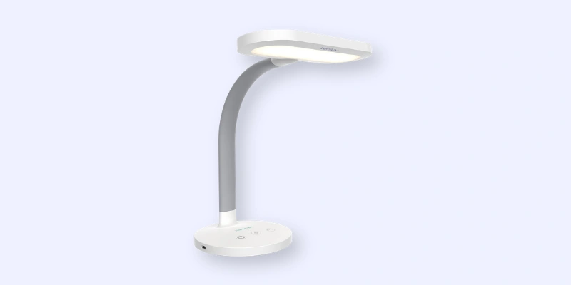 A modern, white desk lamp with a curved gray neck and a flat, oval-shaped light head, shown against a light blue background. The base has touch controls and a power port.