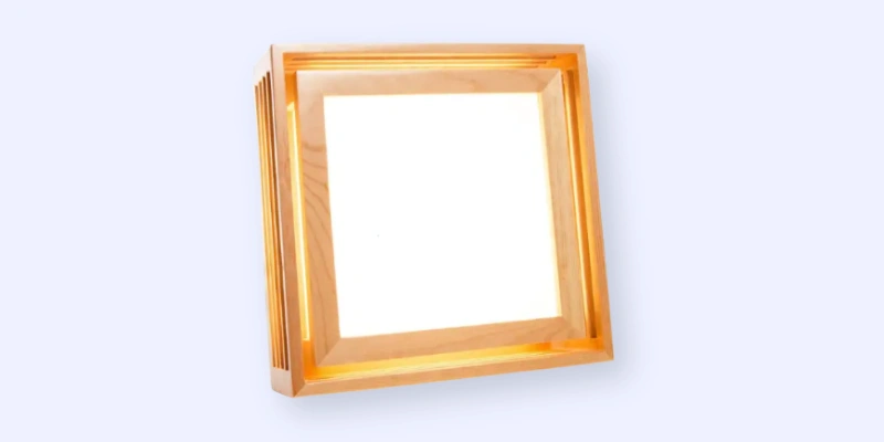A modern, square-shaped wooden wall light with a bright white illuminated center, photographed against a light blue background.