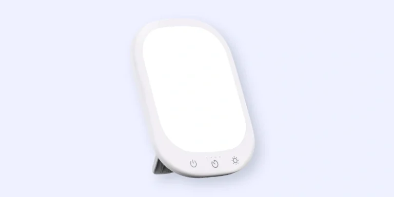 A rectangular white light therapy lamp with rounded corners, featuring a stand and three touch buttons at the bottom for power and brightness adjustment, set against a light background.