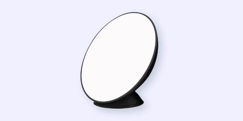 A white, circular satellite dish with a black rim and base, angled to the left, set against a light blue background.