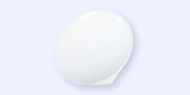 A smooth, white, oval-shaped object is set against a light blue background. The surface is glossy and reflective, giving it a clean and minimalist appearance.