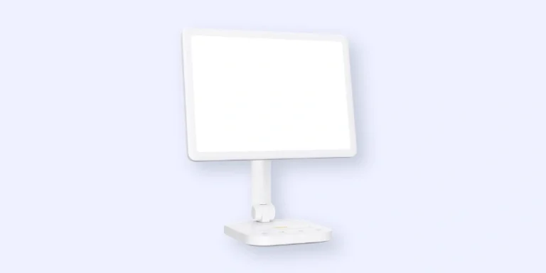 A white touchscreen monitor with a wide, blank display is mounted on a slim, adjustable stand attached to a rectangular base against a light blue background.