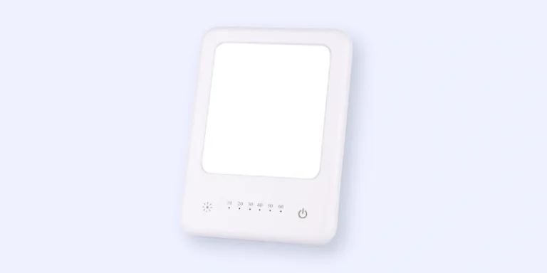 A rectangular white light therapy lamp with a glowing panel, touch controls, a timer display, and a power button on a light blue background.