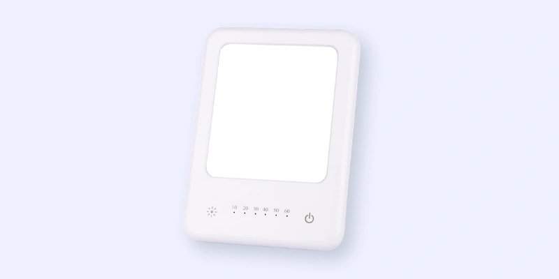 A rectangular white light therapy lamp with a glowing panel, touch controls, a timer display, and a power button on a light blue background.