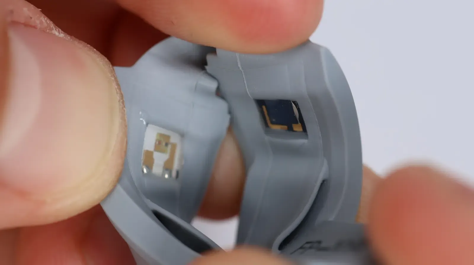 Smart ring teardown showing optical heart rate sensors and health tracking components inside gray wearable device