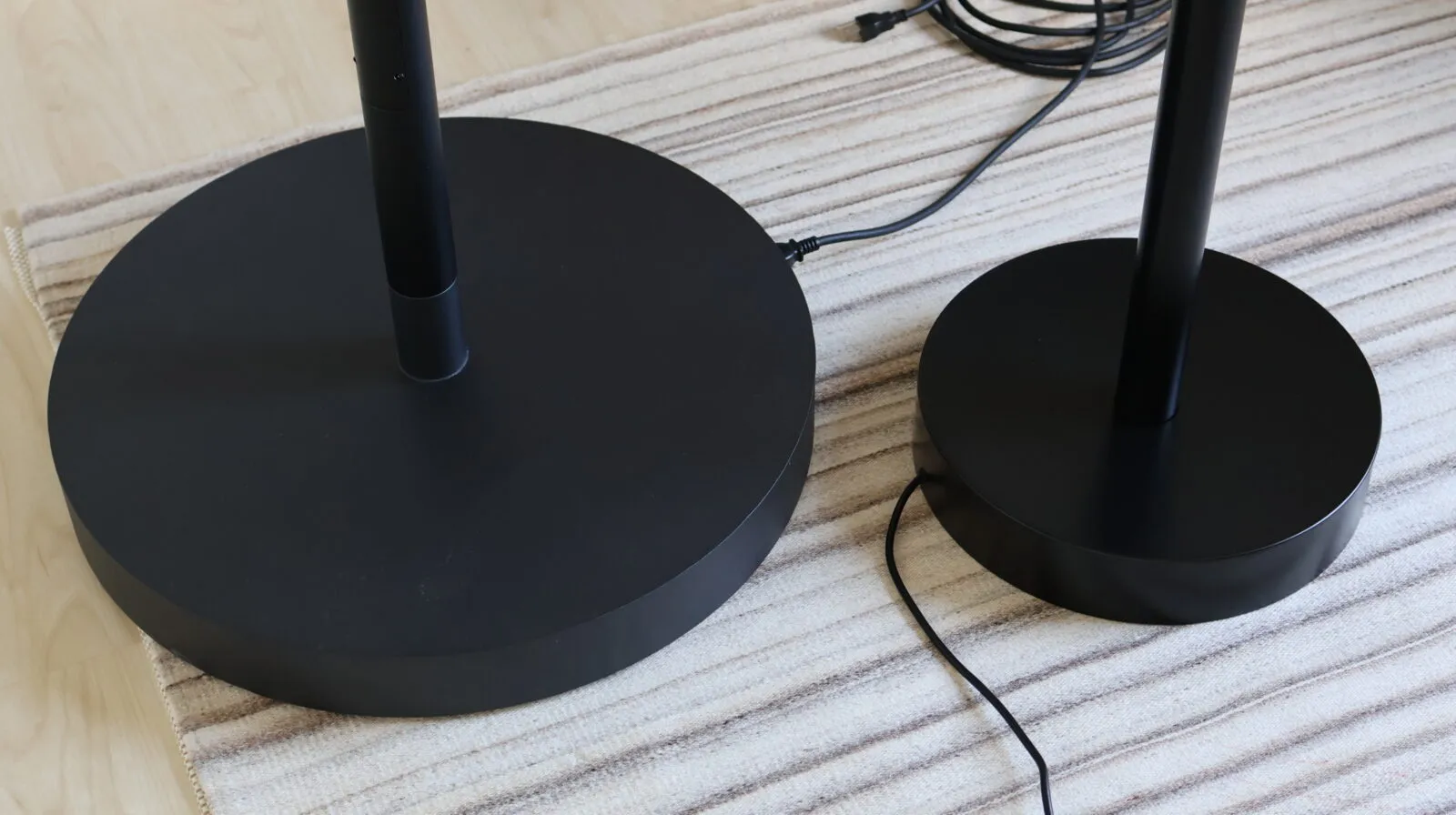 Two black metal floor lamp bases of different sizes=