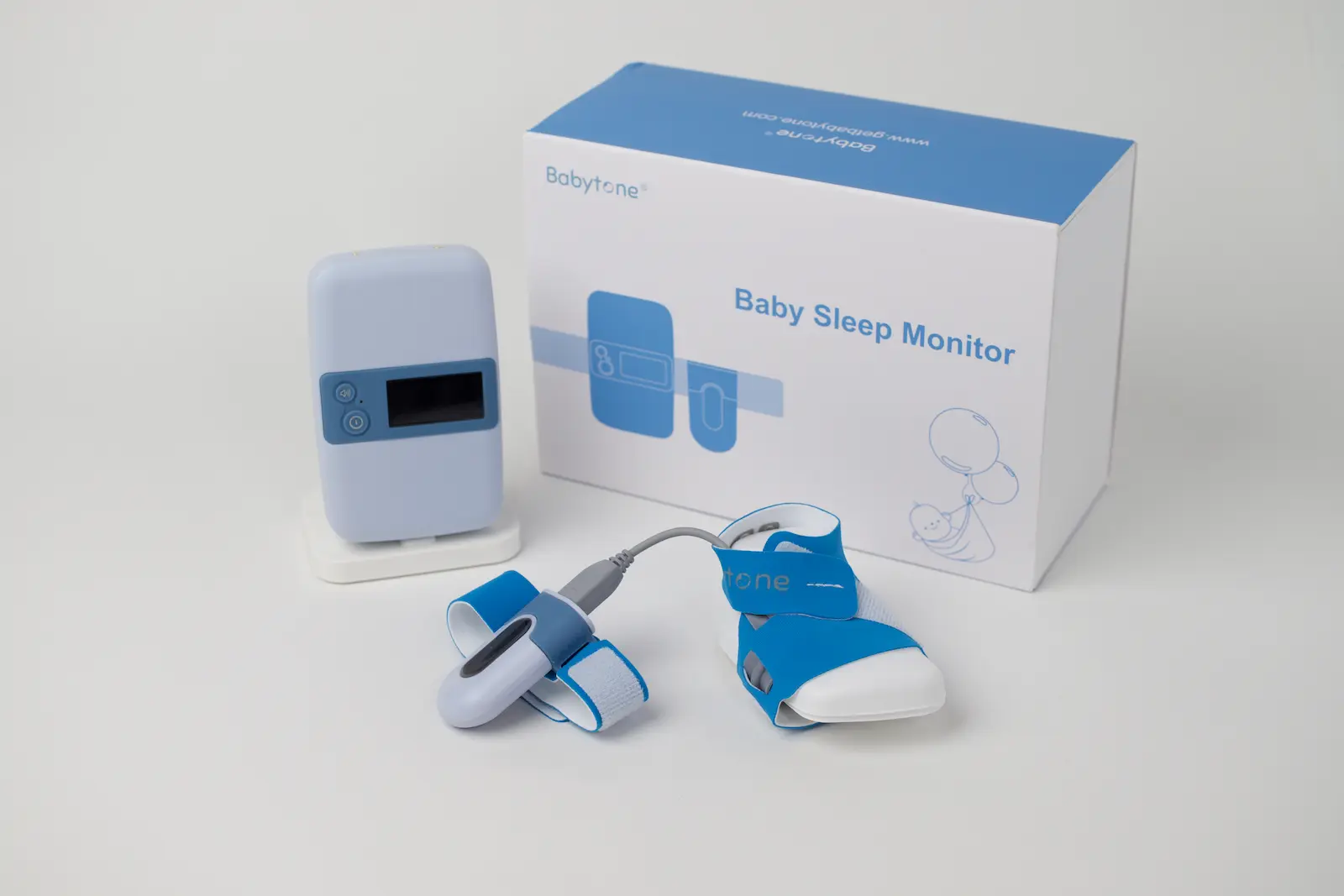 Babytone Baby Sleep Monitor kit with base unit, foot sensor sock, and finger pulse oximeter sensor beside product box