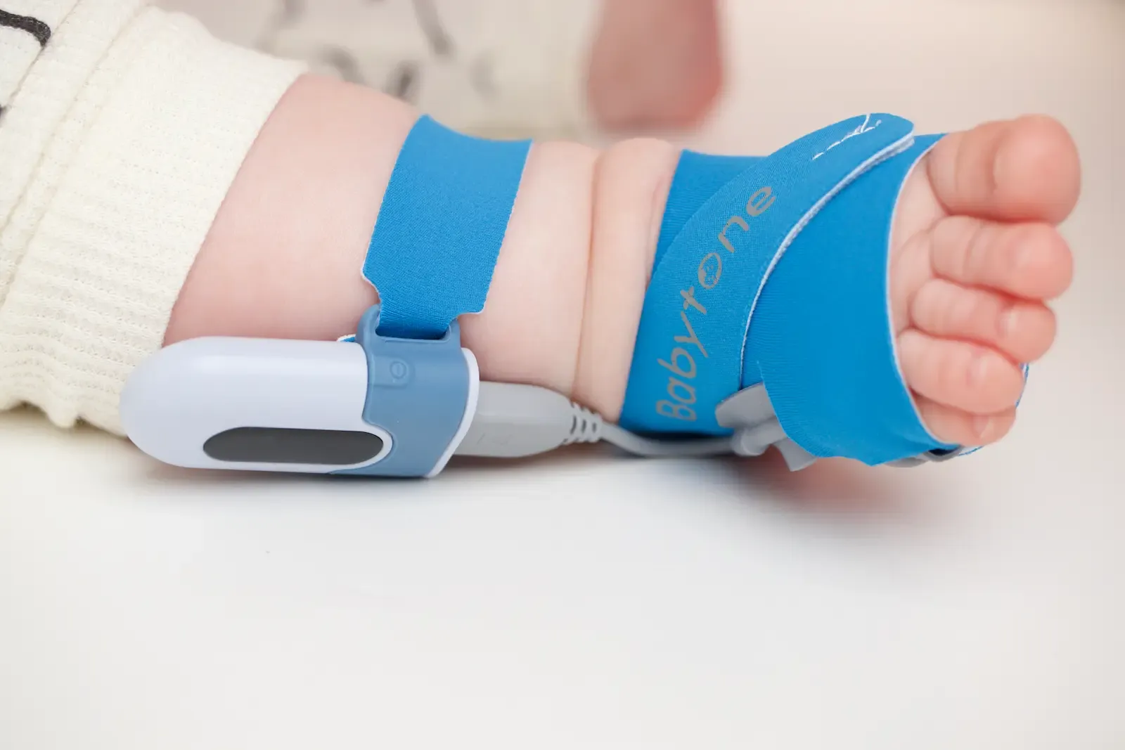 Babytone medical device strapped to a newborn baby's hand and wrist for infant health monitoring