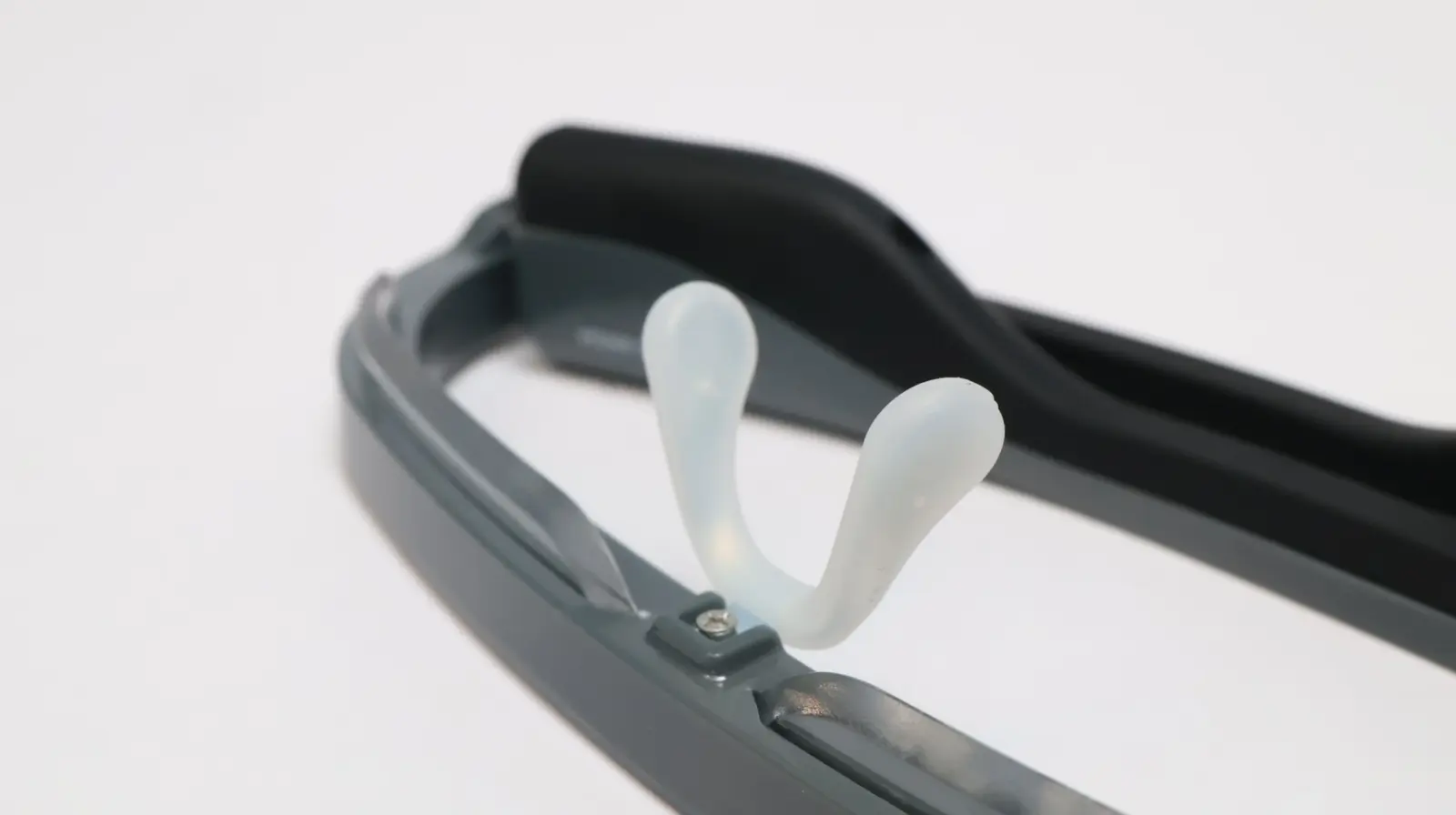 Close-up of gray eyeglass frames with translucent silicone nose pads and black rubber temple tips on white background