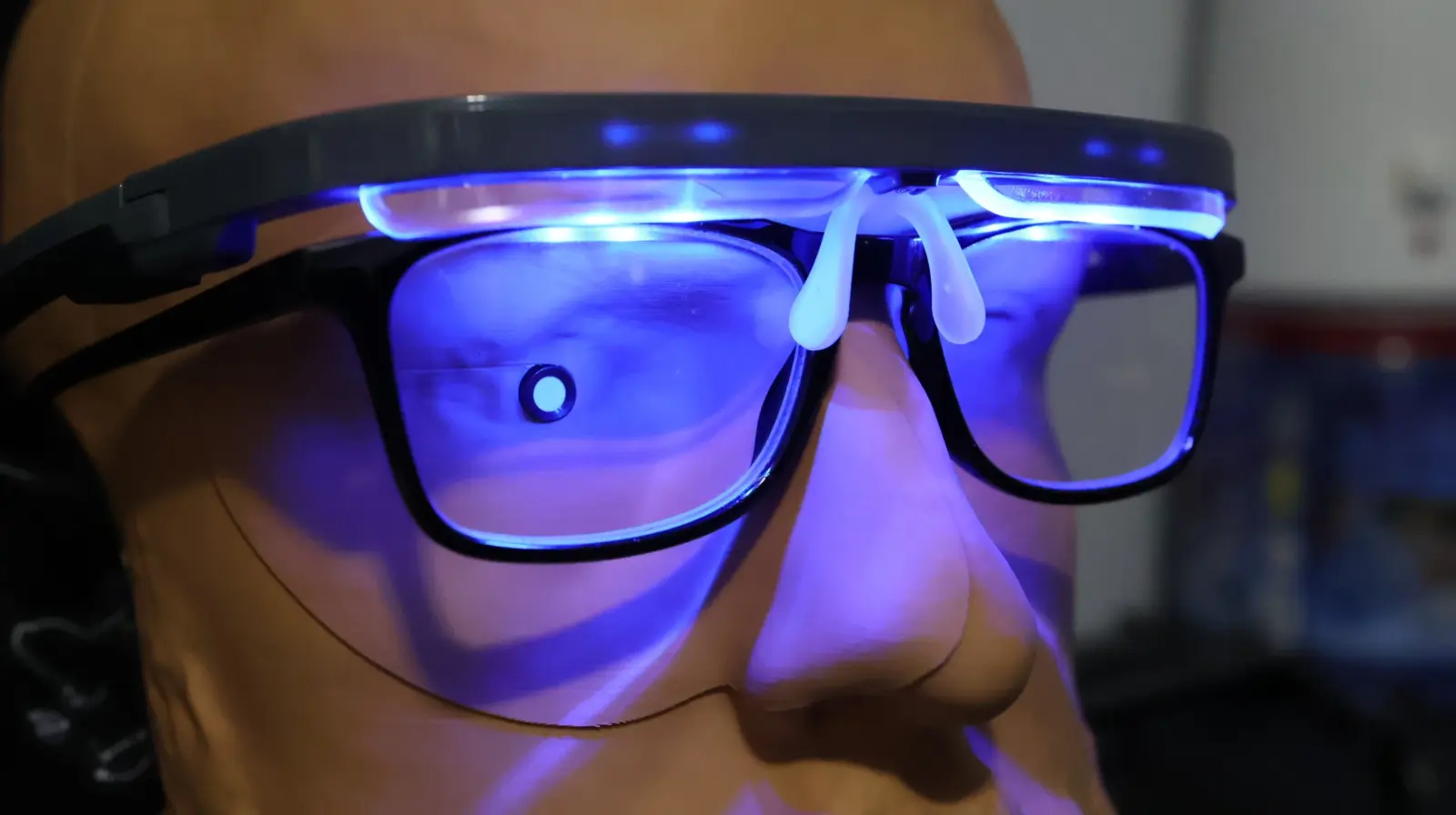 Smart glasses with glowing blue LED lights displayed on a mannequin head, showcasing futuristic wearable tech