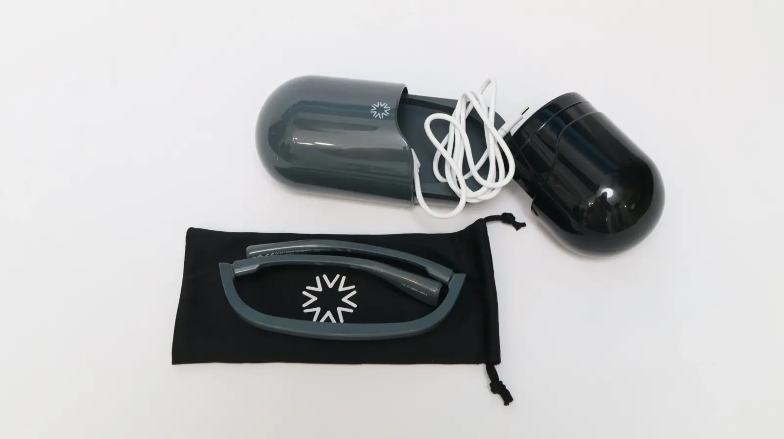 Focals smart glasses by North with pill-shaped charging case, cable, and black drawstring pouch on white background