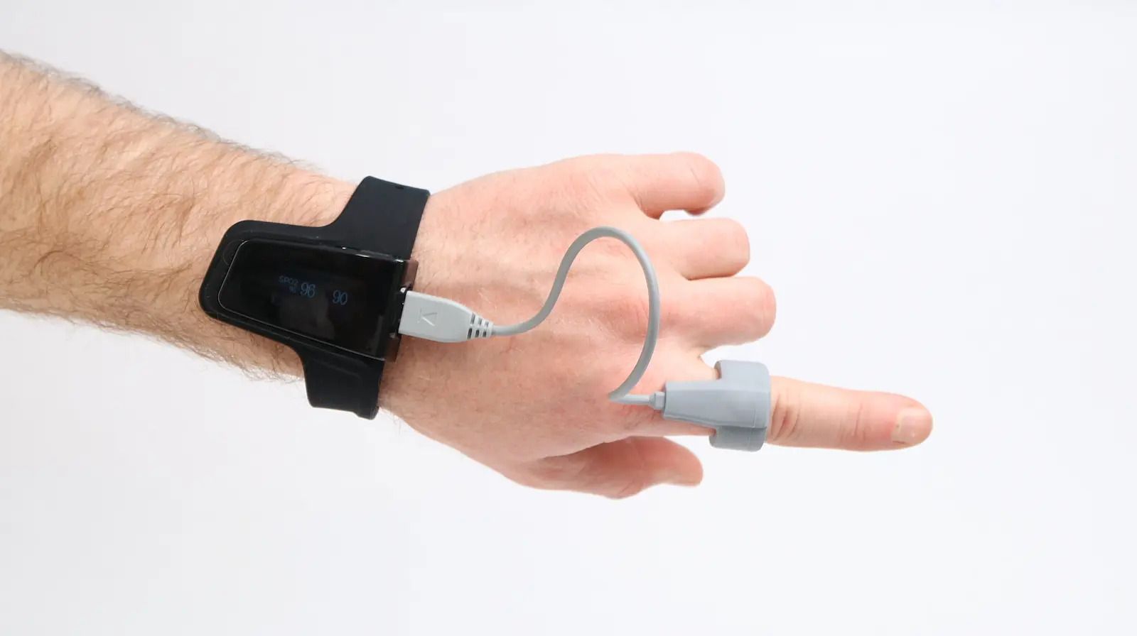 Wrist-worn pulse oximeter with finger SpO2 sensor clip connected by cable, displaying blood oxygen level 96 and heart rate 90
