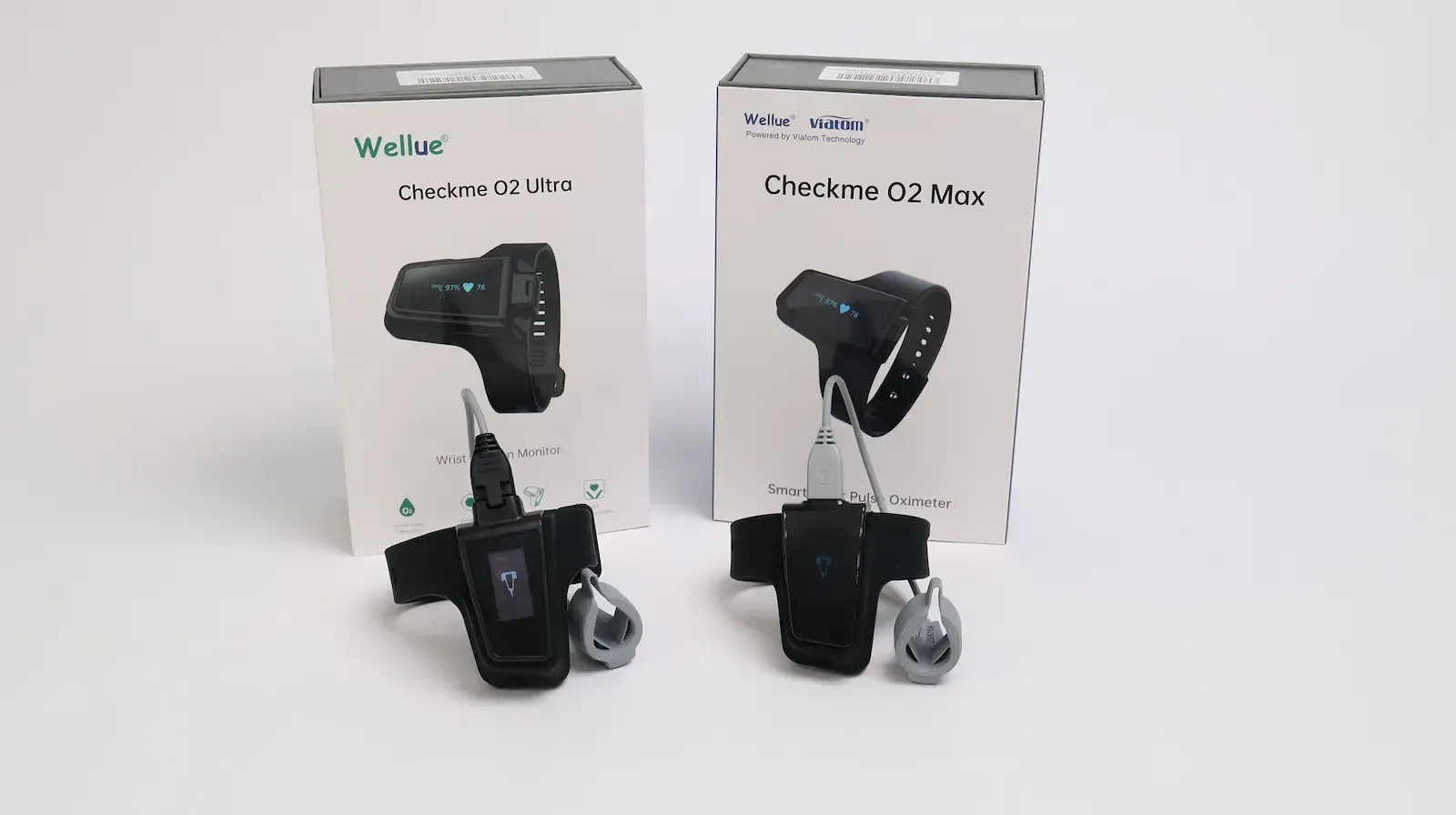 Wellue Checkme O2 Ultra and Checkme O2 Max wrist pulse oximeters with finger probes displayed in front of their boxes
