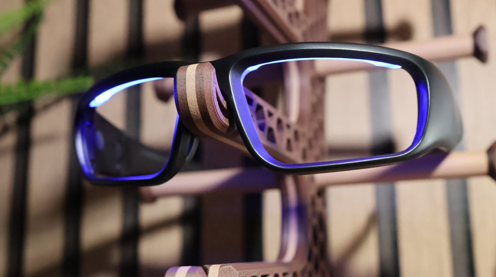 Black frame blue light blocking glasses displayed on a 3D-printed stand with wooden accent bridge