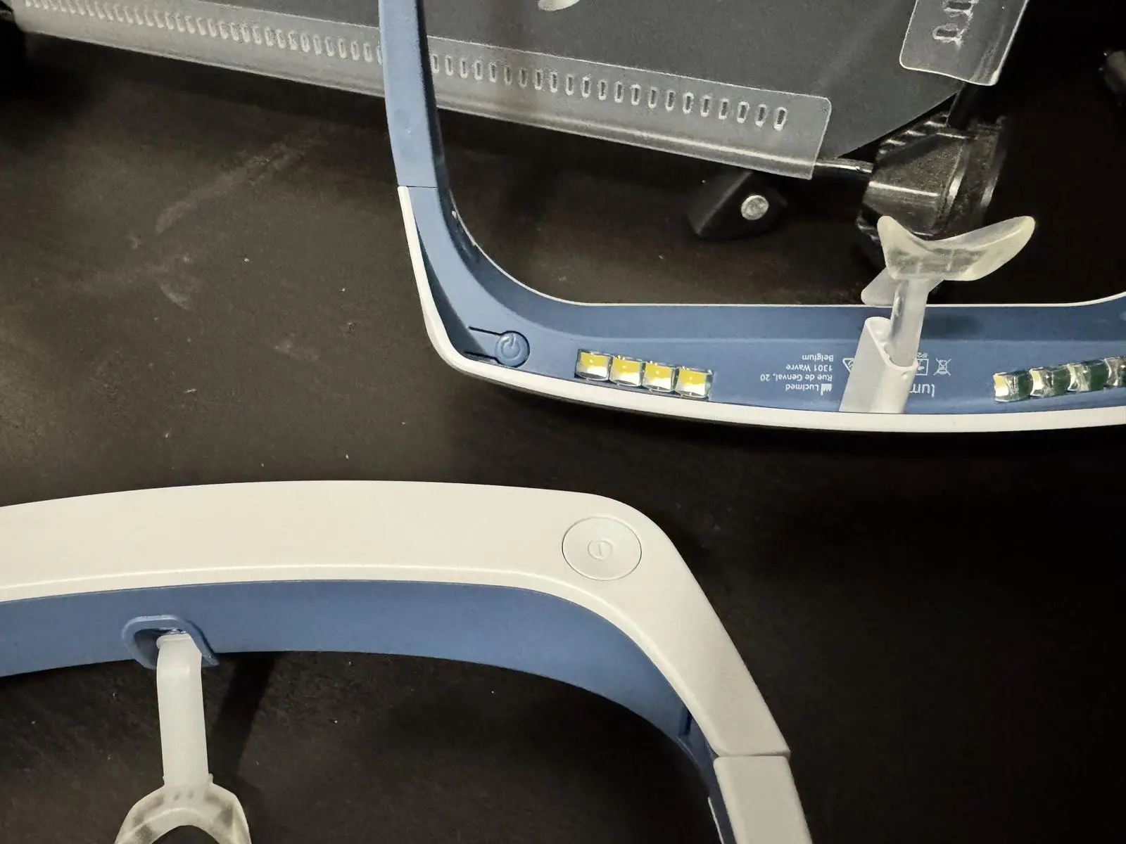Close-up of a Luminette 2 visor with its small power button tucked inside the frame, beside a Luminette 3 with a round top-right button.
